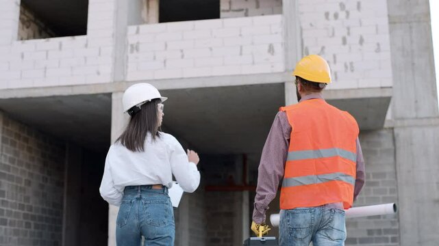 Construction worker collaborates on building site with engineer and discusses project plans
