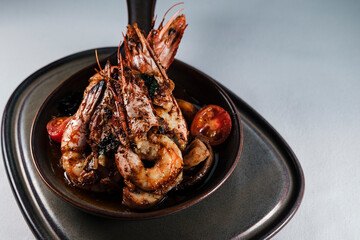 grilled jumbo shrimp casserole or guvec with domatoes, butter garlic sauce and mushrooms served on earth color brown contemporary plates