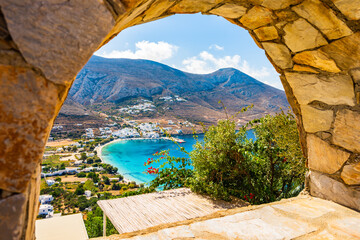 View of Aigiali sea bay with mountains framed by stone arch, Amorgos island, Cyclades, Greece