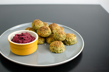 Vegetarian Cauliflower Falafel with Beetroot Dip, in a plate, on a black table, Vegan