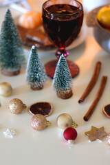 Various Christmas decorations, cookies, chocolate, nuts and tangerines, wine glasses and lit candles on the table. Holiday hygge at home. Selective focus.