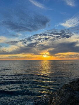 Sunset sky over shiny sea and rocky coast 