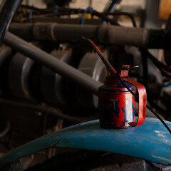 Nahaufnahme einer roten Ölkanne auf einem blauen Kotflügel.