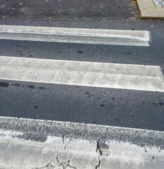 Fototapeta premium A close-up view of a crosswalk with clear white stripes on a gray asphalt road, highlighting urban infrastructure and pedestrian pathways.