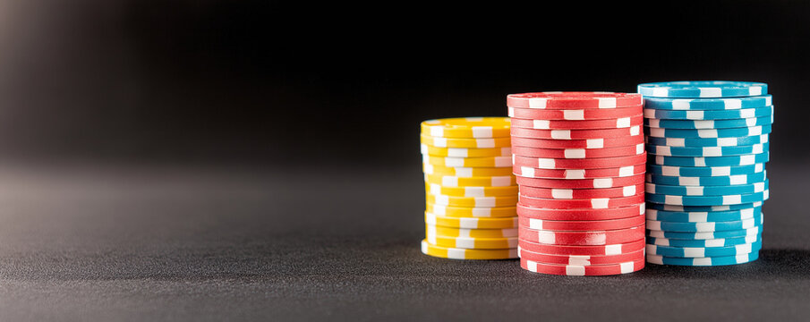 Vibrant casino poker chips vertically stacking, gleaming under soft lighting against dark sleek surface, highlighting gambling elegance