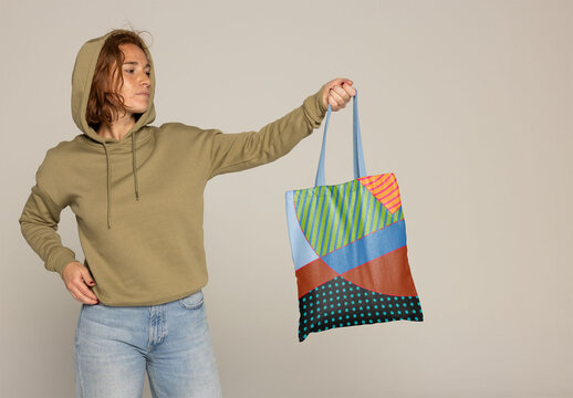 Customizable Tote Bag Displayed by a Woman in Casual Wear. PSD mockup. Insert your design, your logo and change color from bag