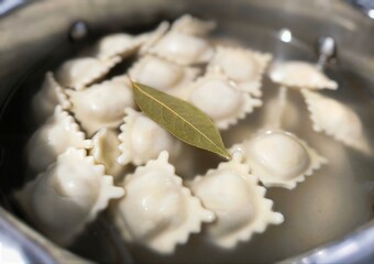 Boiled dumplings are mixed with a large spoon in boiling water. cooking dumplings in a saucepan