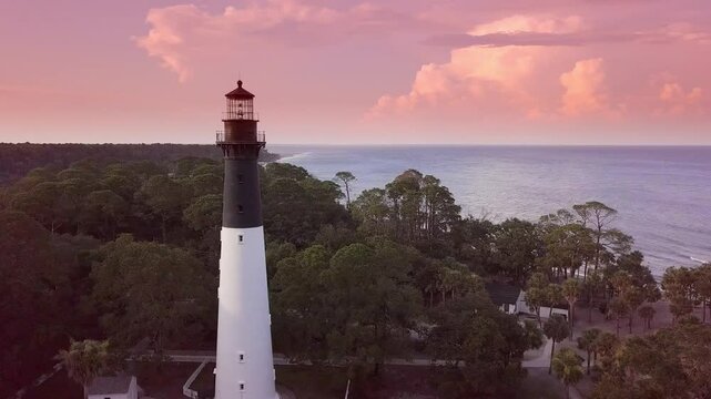 Aerial cinematic circling drone shot of lighthouse at sunset in South Carolina.
