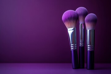 Three natural soft makeup brushes on dark purple background with copy space, professional tool for applying cosmetics.