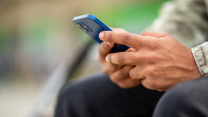 Close-up of hands holding smartphone outdoors