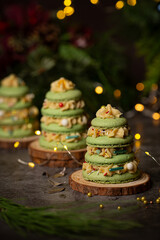 French macaron in the shape of green christmas tree with lights on dark background 