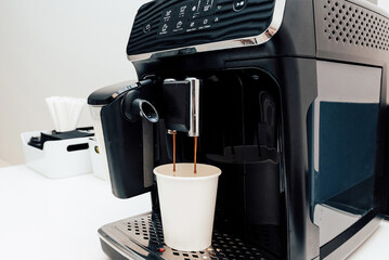 Coffee machine making hot drink in office, table for breaks from work