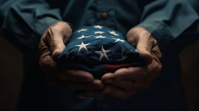 Elderly hands holding folded American flag in dim light