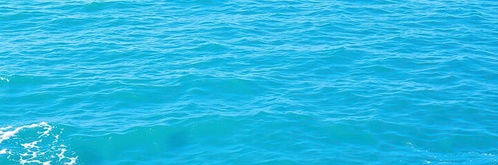 The pure blue turquoise water of the ocean sea creates a mesmerizing texture with foamy waves, peaceful, beauty