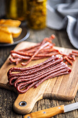 Smoked kabanos. Mini dried thin sausages on cutting board on wooden table.