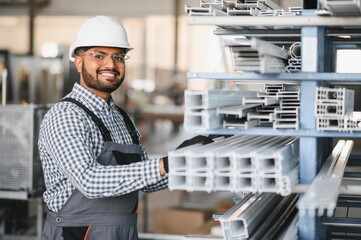 Operator of machine. Industrial worker indoors in factory. Young technician in white hard hat