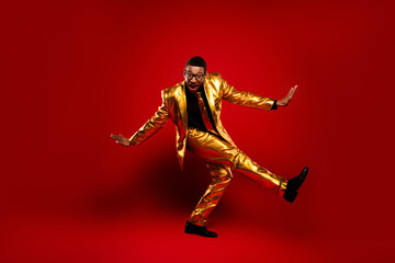 Young man in golden suit against red background showcasing charm and charisma. Perfect image for...