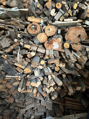 Stacked firewood ready for winter use in a rustic cabin setting near a forested area during daytime