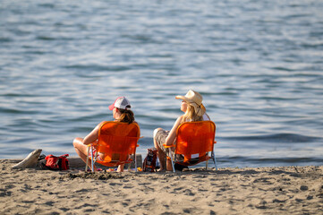 Two female friends sitting at the beach.
