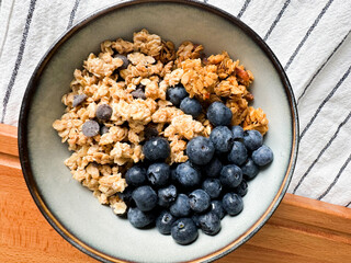 Healthy breakfast bowl with granola and fresh blueberries on a wooden surface