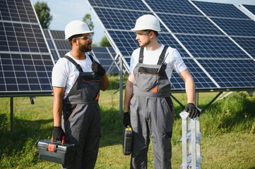 Two skilled workers or craftsmen wearing working gray uniforms, technicians are installing solar panels on a solar farm for clean energy and electricity supply