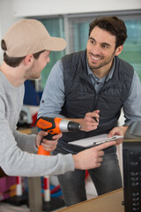 two men in workwear in a carpenters workshop with parcel