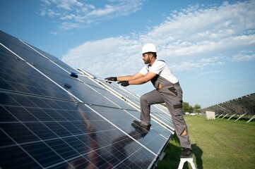 Indian handyman cleaning solar panels form dust and dirt