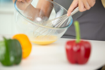 female chef beating eggs with wire whisk in bowl