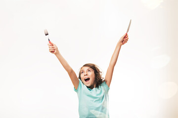Excited girl holding fork and knife up in the air