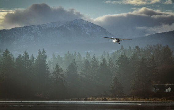 Scenic Light Aircraft Landing Over Misty Forest and Mountain Landscape. Cessna 172 single engine aircraft