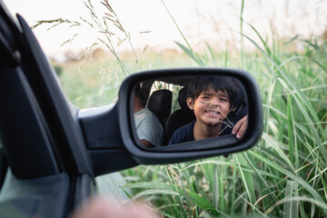 smiling girl with short dark hair watching herself in a side mirror of a car