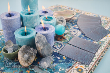 Mystical Card Reading Setup. Blue candles, crystals, and tarot cards on a patterned cloth.