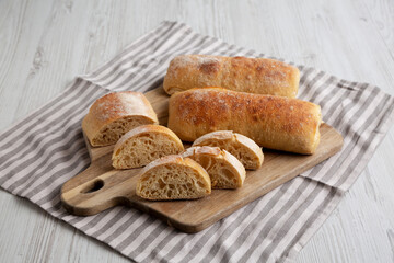 Homemade Sliced Ciabatta Bread on a wooden board, side view.