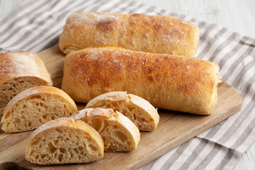 Homemade Sliced Ciabatta Bread on a wooden board, side view.