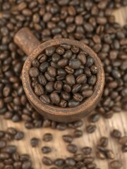 Fototapeta premium Dark roasted coffee beans overflowing from a rustic wooden cup, coffee,coffee beans