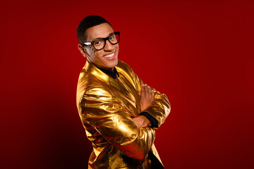 A charismatic gentleman in a golden suit stands confidently against a vibrant red background