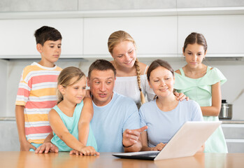 Large family uses a laptop to communicate with friends and relatives via the Internet