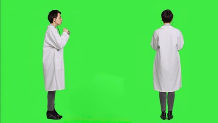 Woman physician is using a stethoscope to listen to breathing in studio, wearing a white hospital coat against greenscreen backdrop. Medic with professional expertise does consultations. Camera A.