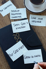 2025 Christian goals handwritten on notes on wooden desk. Top view. Spiritual growth, faith, love,...