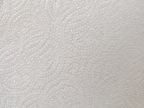 Close-up macro view of white embossed kitchen paper towel texture details with circular patterns design. Soft textured absorbent material for households cleaning and wiping surfaces efficiently. 