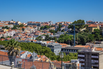 Obraz premium Panoramic view of Lisbon cityscape, showcasing terracotta rooftops, traditional and modern architecture under a clear blue sky. Lisbon, Portugal. 