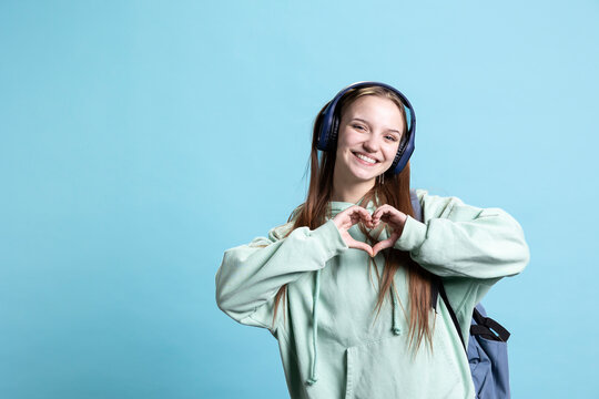 Portrait of friendly smiling woman doing heart symbol shape gesture with hands, being affectionate. Cheerful nurturing person showing love gesturing, isolated over studio background