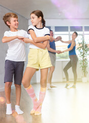 Fototapeta premium Young boy and girl dancing salsa in studio during group training