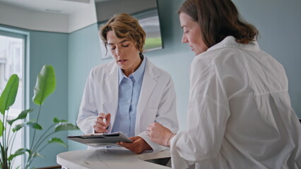 Medical workers reviewing paperwork in modern clinic closeup. Woman doctor 