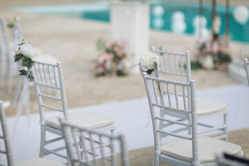 Ceremony in the bosom of nature. White chairs with flowers set in the grass. white chairs lined up for an event accompanied by a bouquet of white flowers.