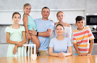 Portrait of happy family - father and mother with four children at the table at home