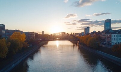 Naklejka premium Sunset over river with bridge and city skyline.