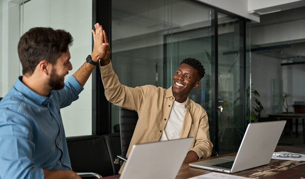 Happy motivated diverse young business men colleagues work team partners giving high five celebrating great corporate achievement, startup project growth, trust in partnership and teamwork concept.