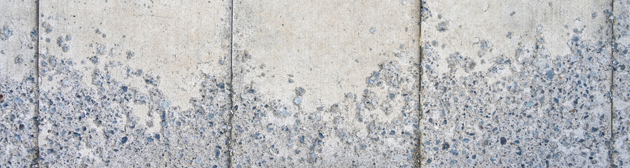 Obraz premium New cement sidewalk weathered and worn with aggregate rocks showing through the erosion, as a gray textured background 