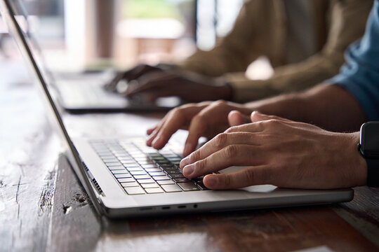 Close up photo of male hands typing on laptop sitting at office desk. Business man software engineer using computer at work searching in internet, working with ai tech online, doing digital management